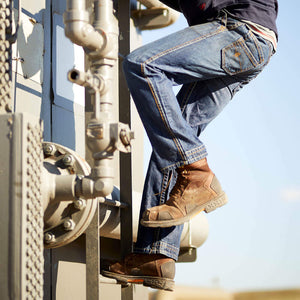 A man climbing a ladder wearing Ariat FR M4 Boot Cut Jean
