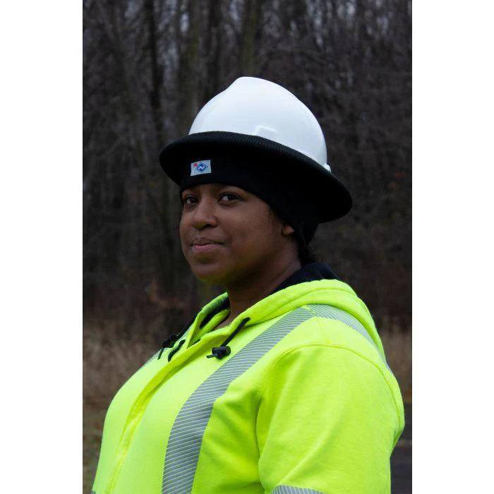 Person wearing a bright yellow safety jacket and white hard hat outdoors
